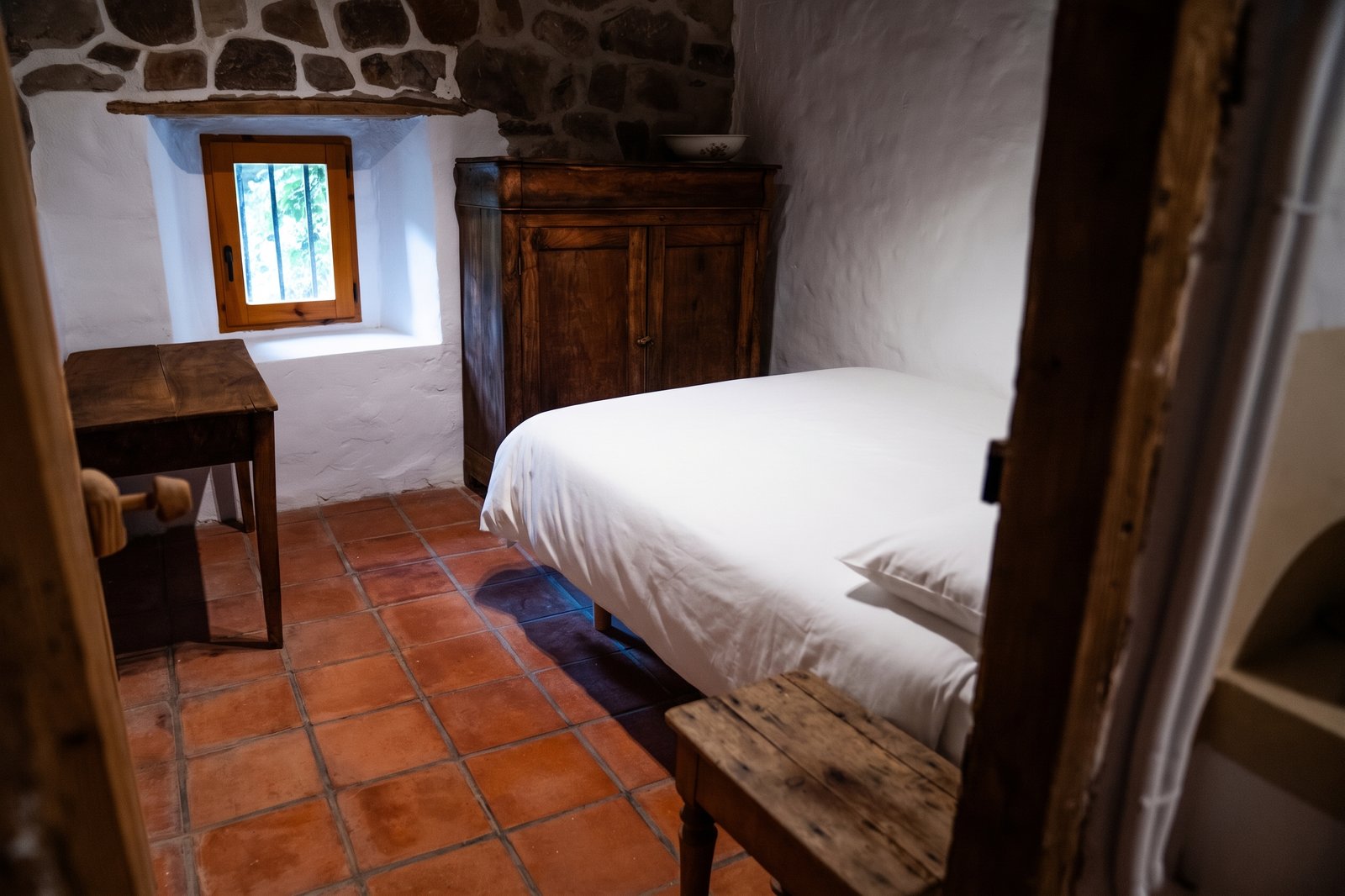 Habitación con armario antiguo y ventana en muro de piedra